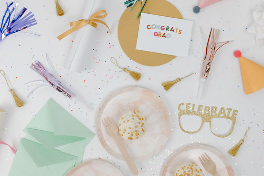 A flat lay composition of colorful graduation party supplies including cards, confetti, and decorations.