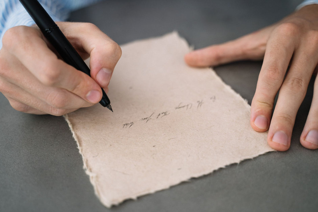 Hands writing in calligraphy on rustic parchment paper. Perfect for vintage or artistic themes.